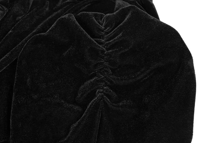 Close-up of black velvet crop top with gathered shoulders and embroidered knot trim