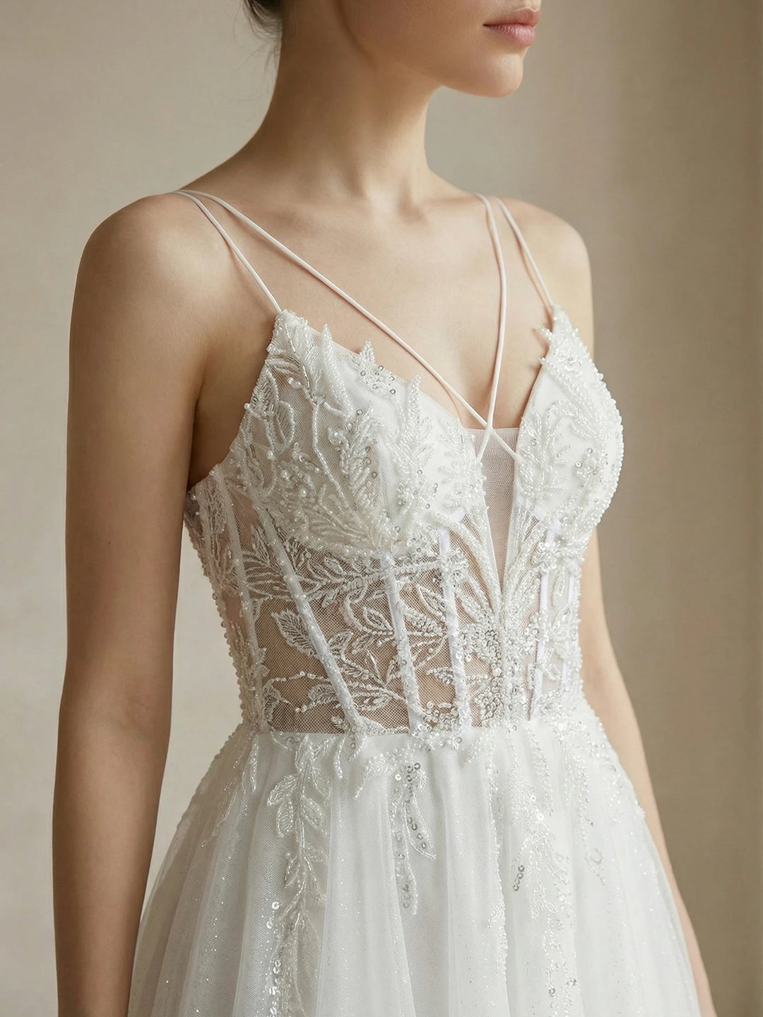 White bridal gown with beaded lace appliqués, deep V bodice, and spaghetti straps