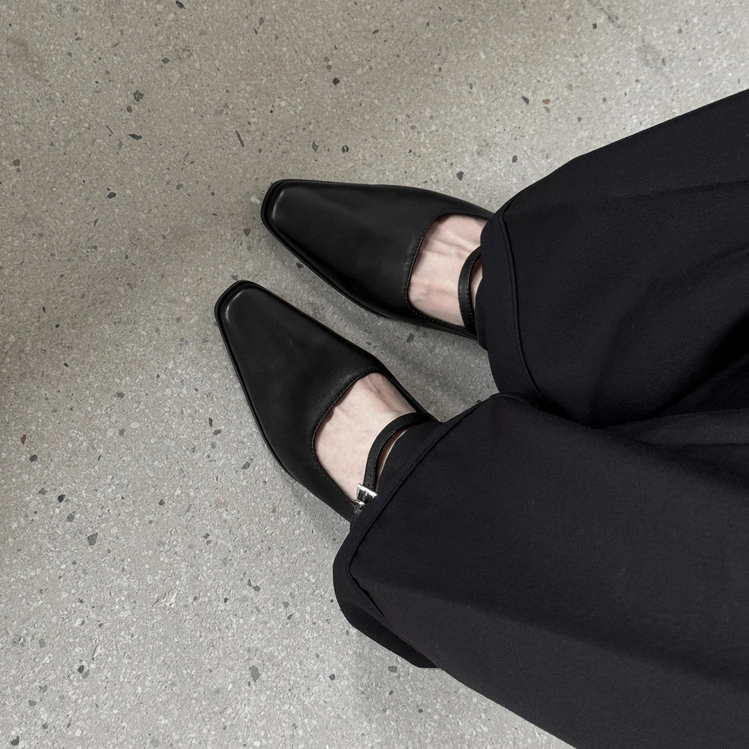 Black leather kitten heel pumps with ankle strap, paired with brown pumps