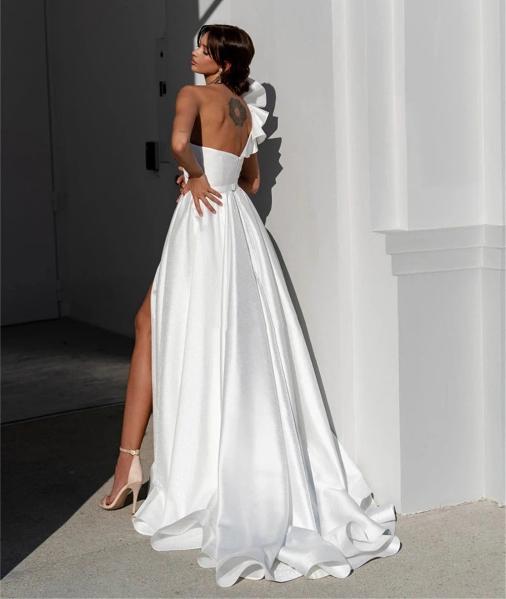 White satin one-shoulder wedding dress with open back and flowing skirt
