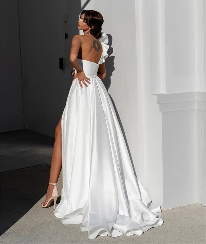 White satin one-shoulder wedding dress with open back and flowing skirt