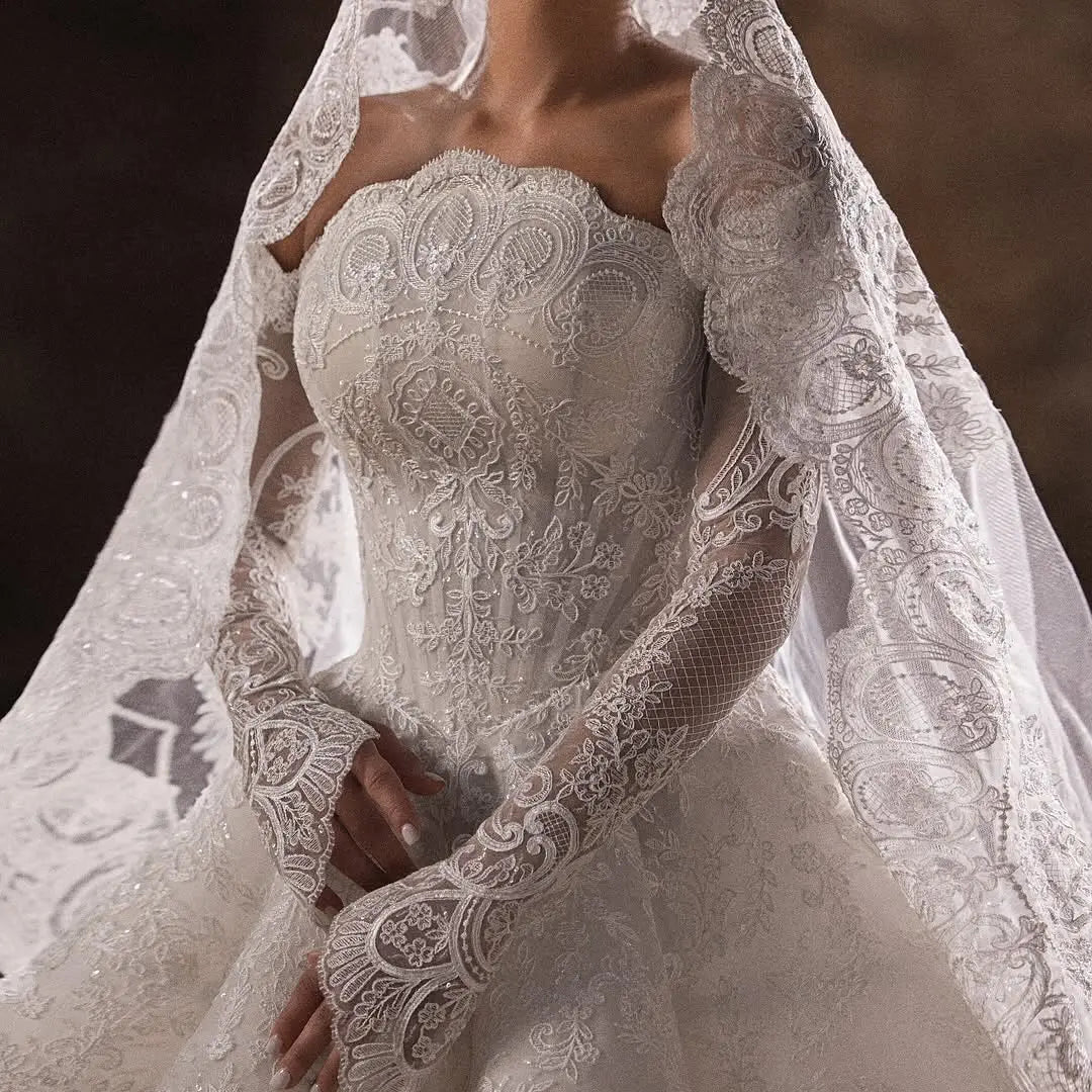 Close-up of white lace bodice with ornate embroidery and long illusion sleeves, veil