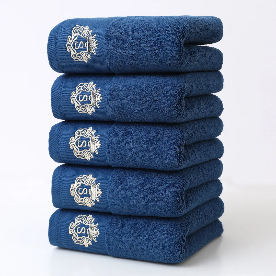 Blue 5-piece bathroom towel set with gold embroidered monograms, folded stack