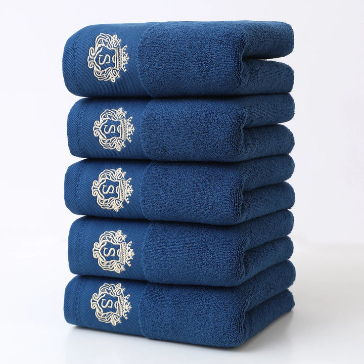 Blue 5-piece bathroom towel set with gold embroidered monograms, folded stack