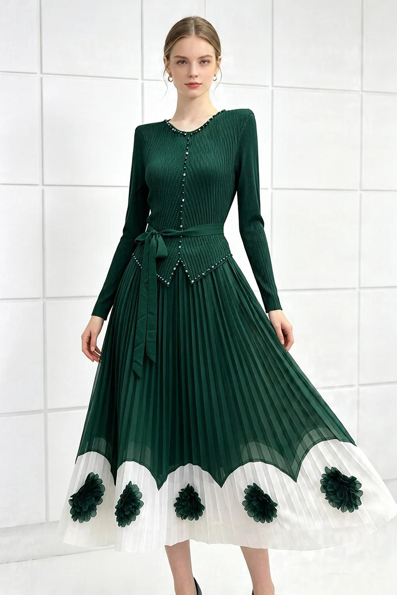 Dark green pleated midi party dress with long sleeves, tie waist, scalloped pom hem with floral trim.