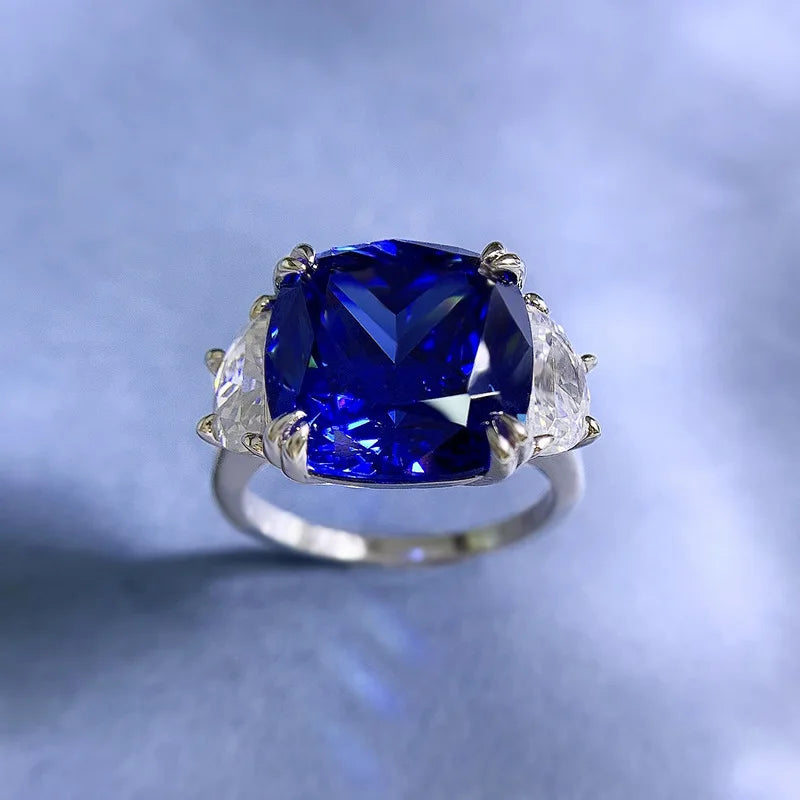 Blue cushion-cut center stone in sterling silver ring with clear side stones