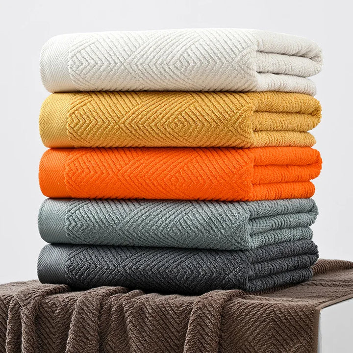 Cotton towel set with mixed colors: white, mustard, orange, and blue-gray, folded stack