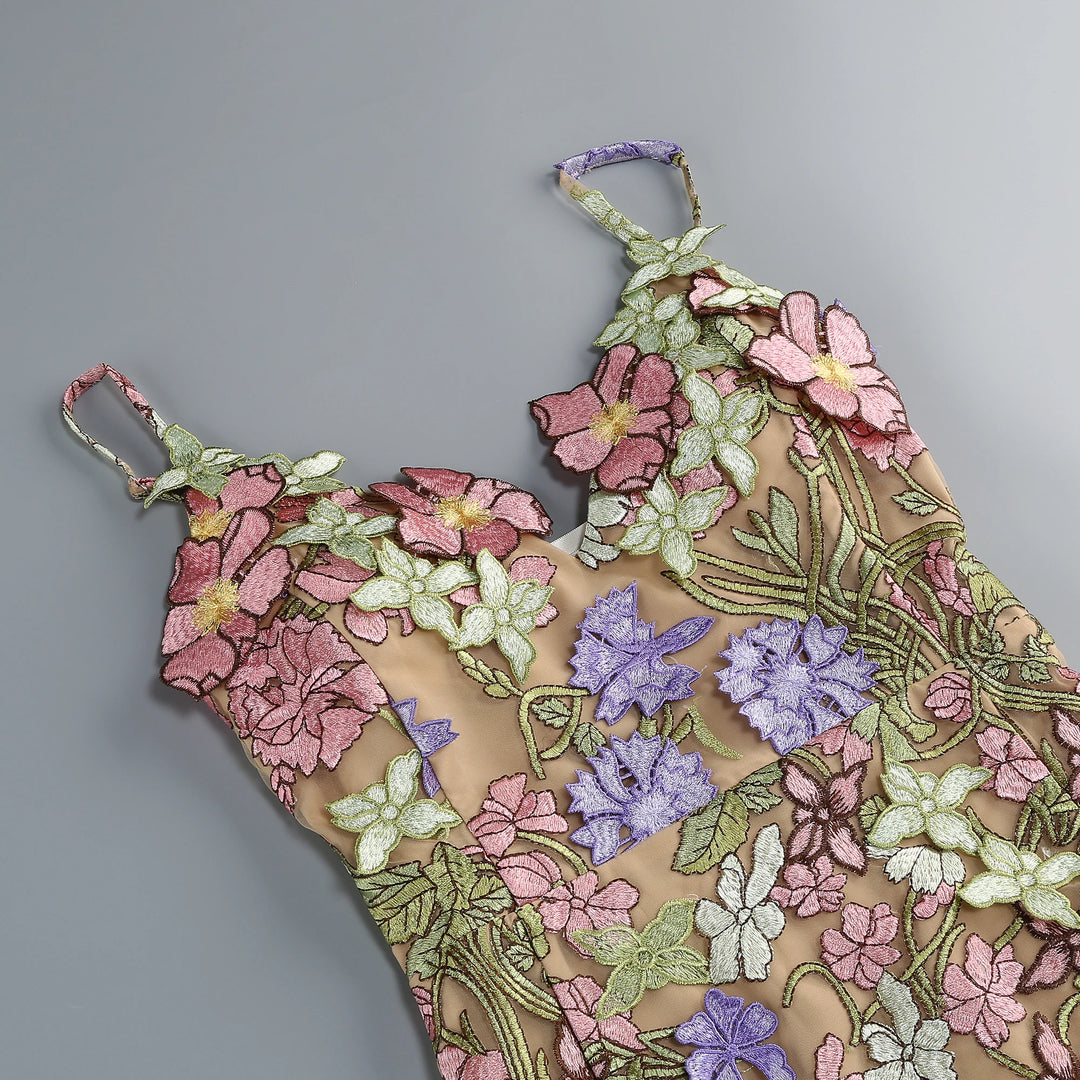 Close-up of multicolor floral embroidery appliques on pink sheer mini gown fabric.