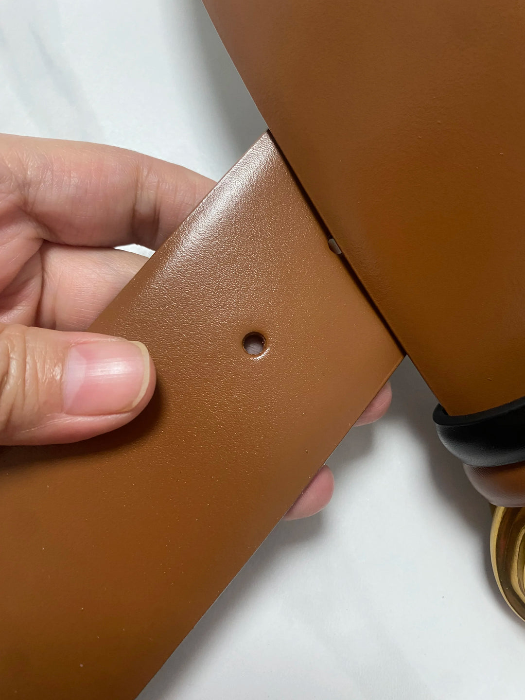 Tan-brown wide leather belt end with stitch edge, round holes, and black backing strap