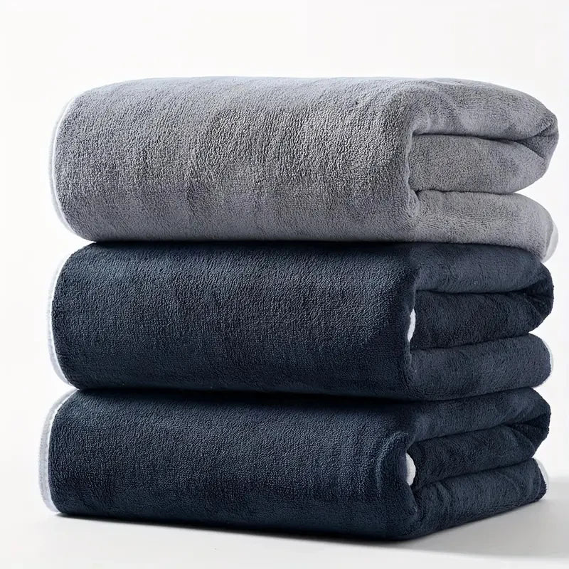Plush velvet bath towel set in light gray and dark navy, folded and stacked.