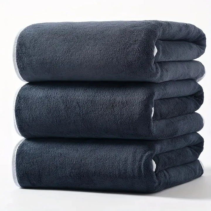 Plush velvet bath towel set in dark gray, folded and neatly stacked.