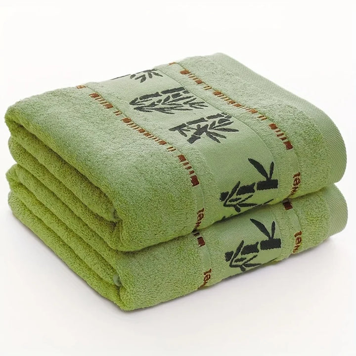 Stacked green towels with black bamboo-pattern band