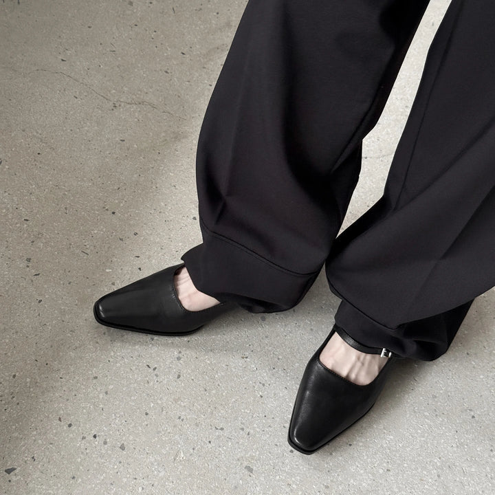 Black kitten heel pumps with ankle strap buckle, worn with dark pants