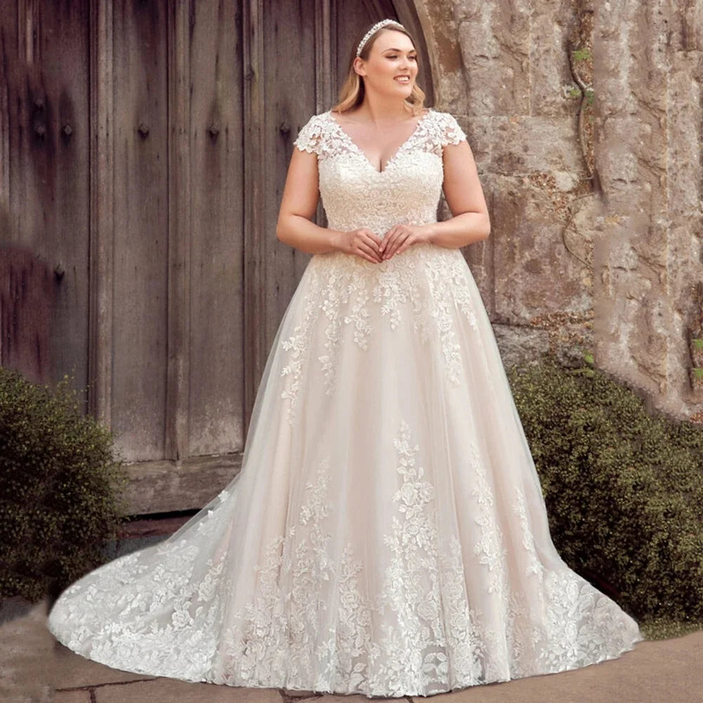 Woman wearing a white lace wedding dress standing outdoors against a rustic wooden wall.