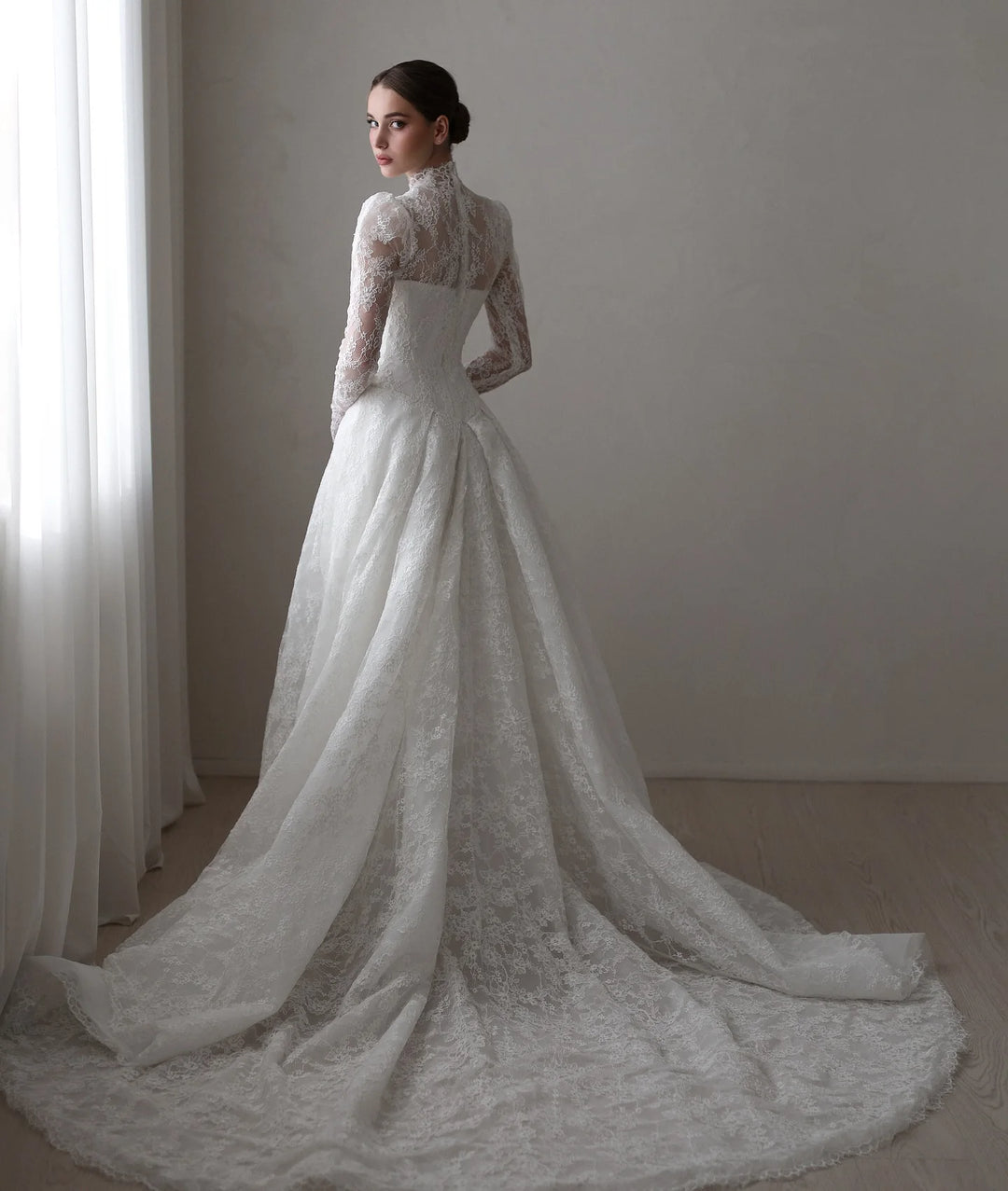 White A-line bridal gown with lace long sleeves and flowing lace skirt with soft train