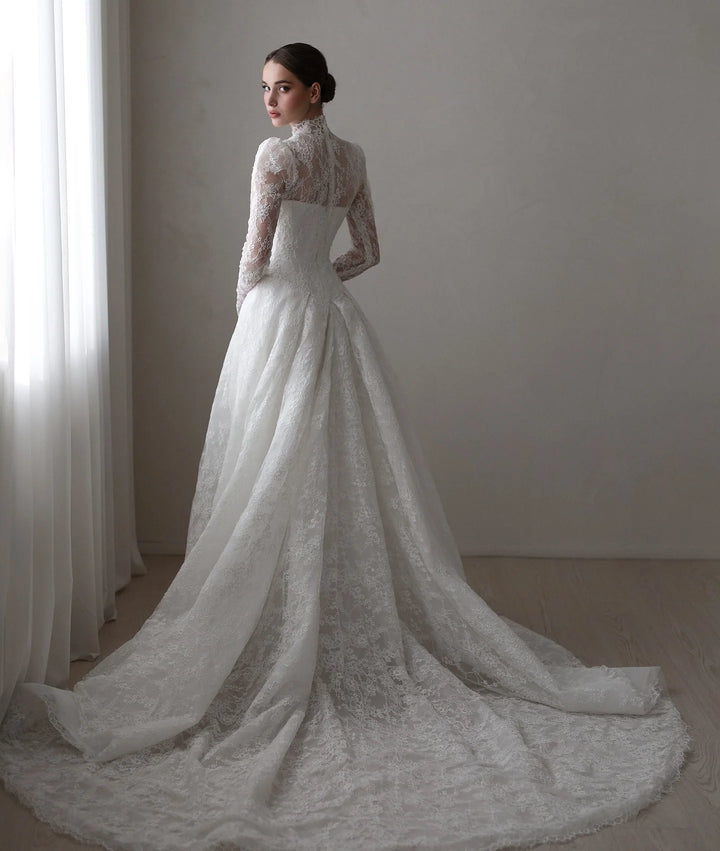 White A-line bridal gown with lace long sleeves and flowing lace skirt with soft train