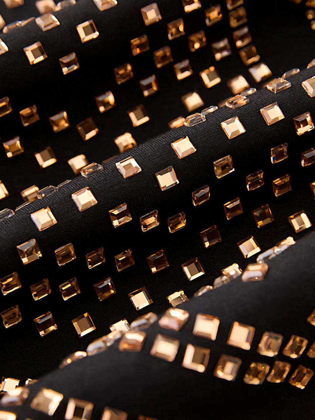 Close-up of square gold rhinestones on black blazer fabric