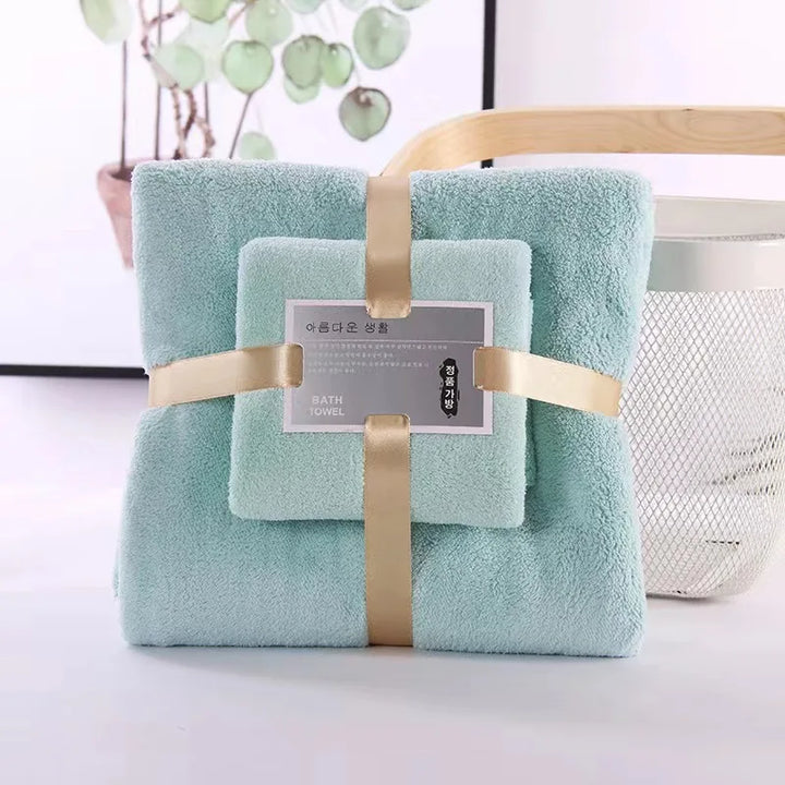 Plush teal 2-piece bath towel set with folded towels, beige ribbon wrap, and label