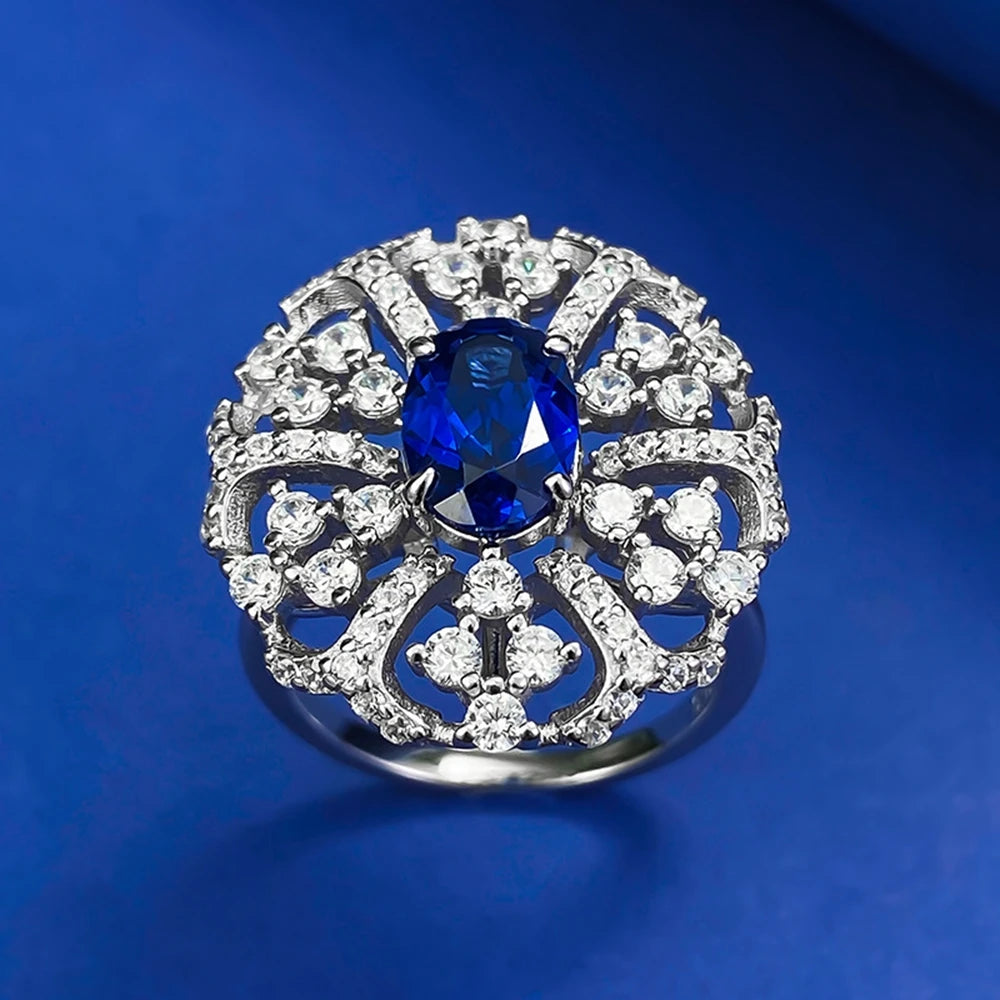 Silver halo ring featuring oval blue center gemstone surrounded by clear cluster stones