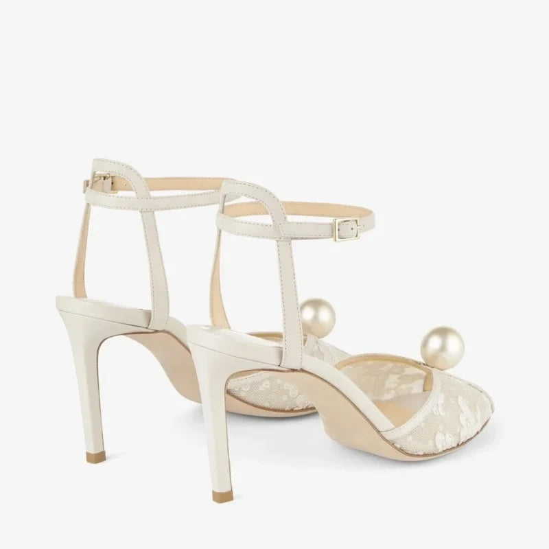 White open-toe high heel sandals with ankle straps, lace uppers, and pearl accents