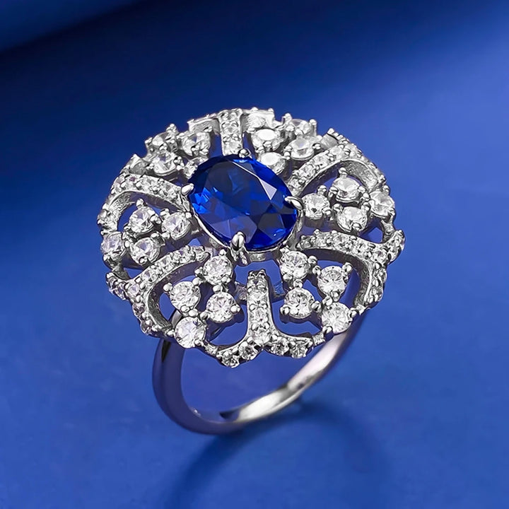 Silver ring with large oval blue center stone and circular halo of clear crystals