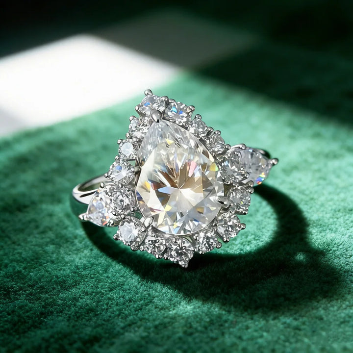 Pear-cut diamond ring with halo surround and three-stone side sparkle detail