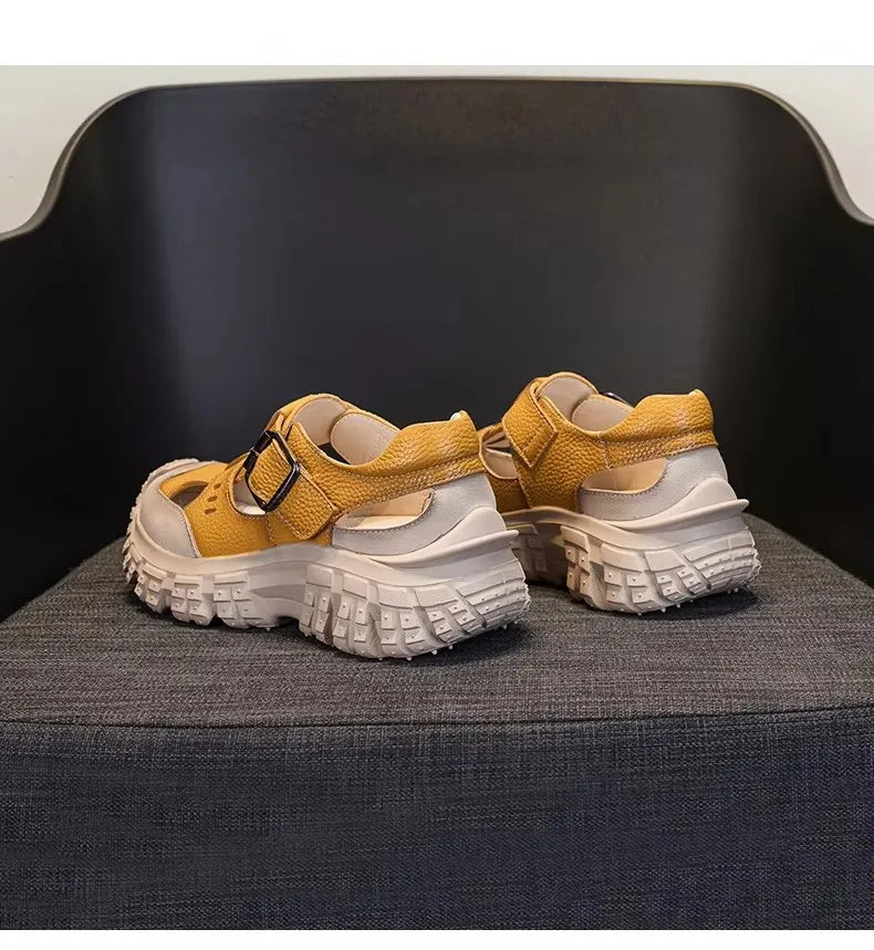 Yellow chunky sandals pair on dark chair with double strap design and tread sole