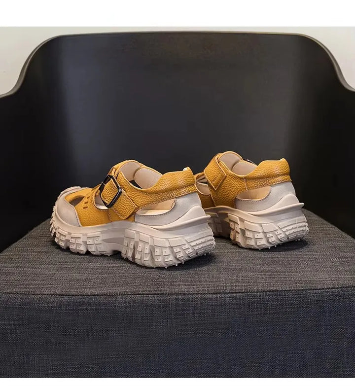 Yellow chunky sandals pair on dark chair with double strap design and tread sole