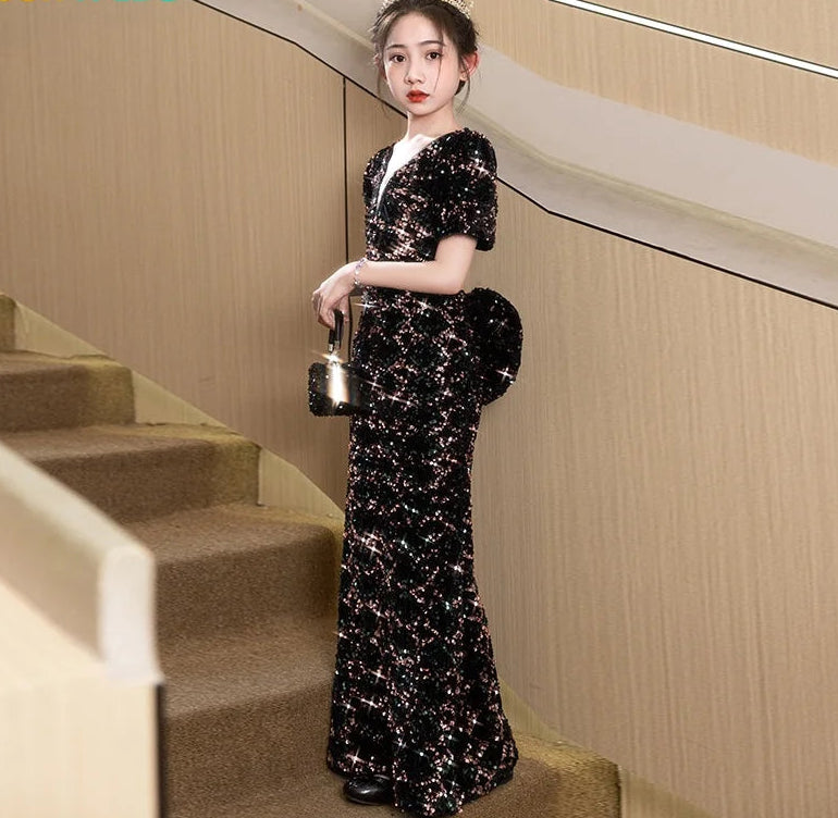 Woman in a black sequin dress standing on a staircase with &