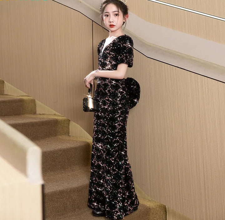 Woman in a black sequin dress standing on a staircase with &