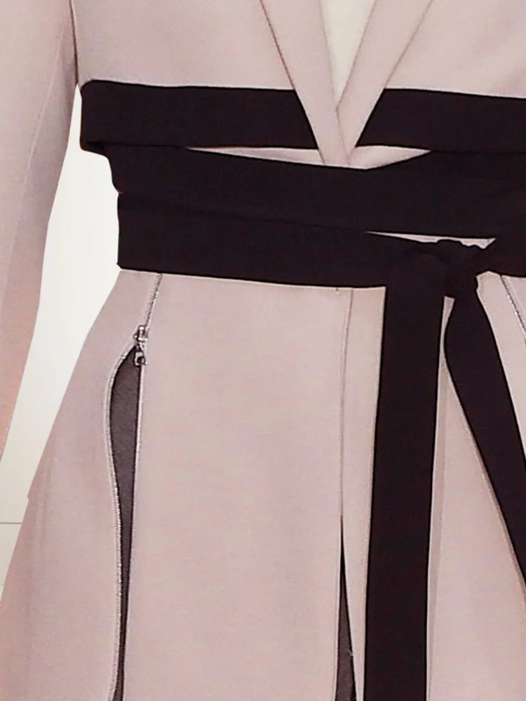 Pink blazer with black waist tie and dangling zipper trim details