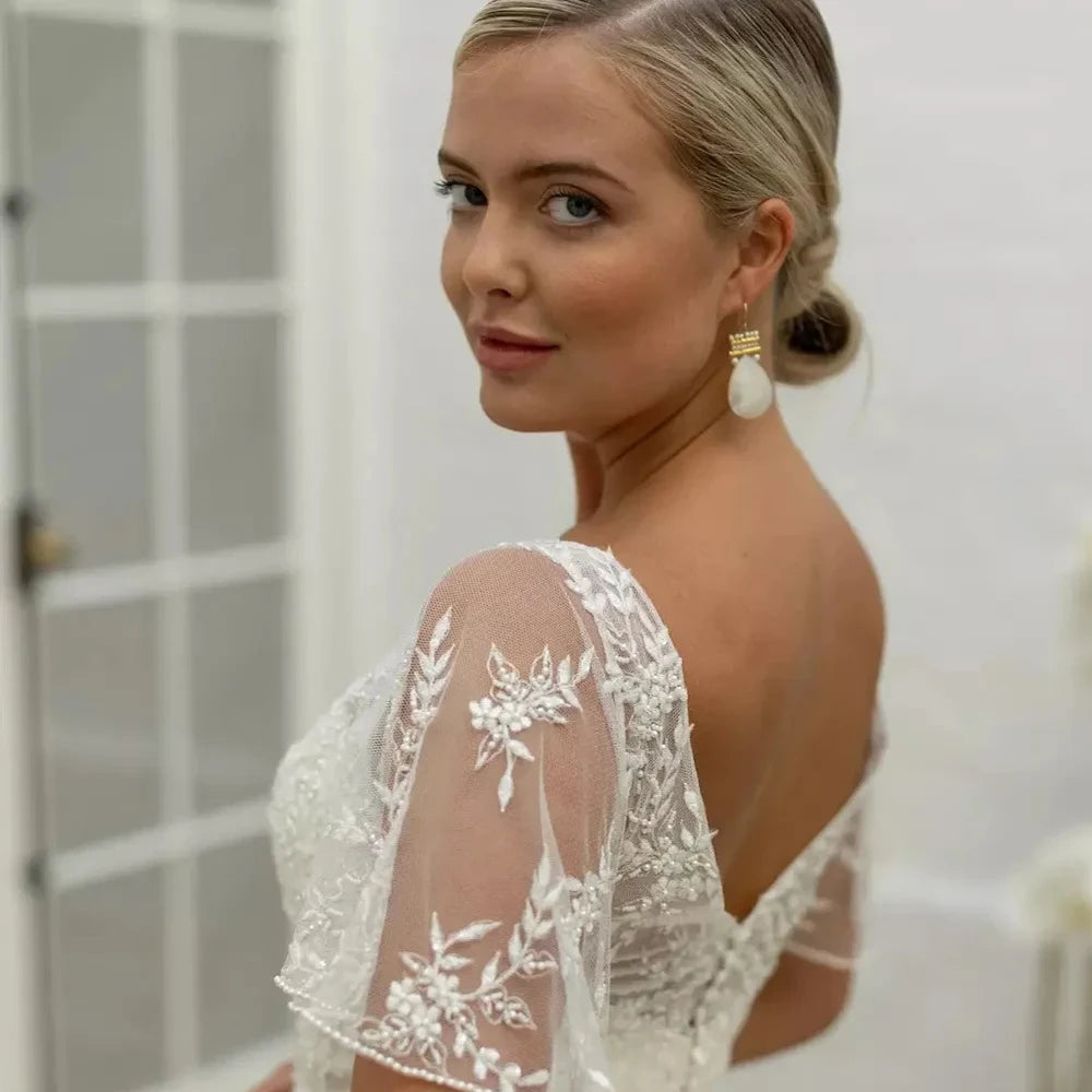 Ivory bridal dress bodice close-up with floral lace appliques on sheer sleeves