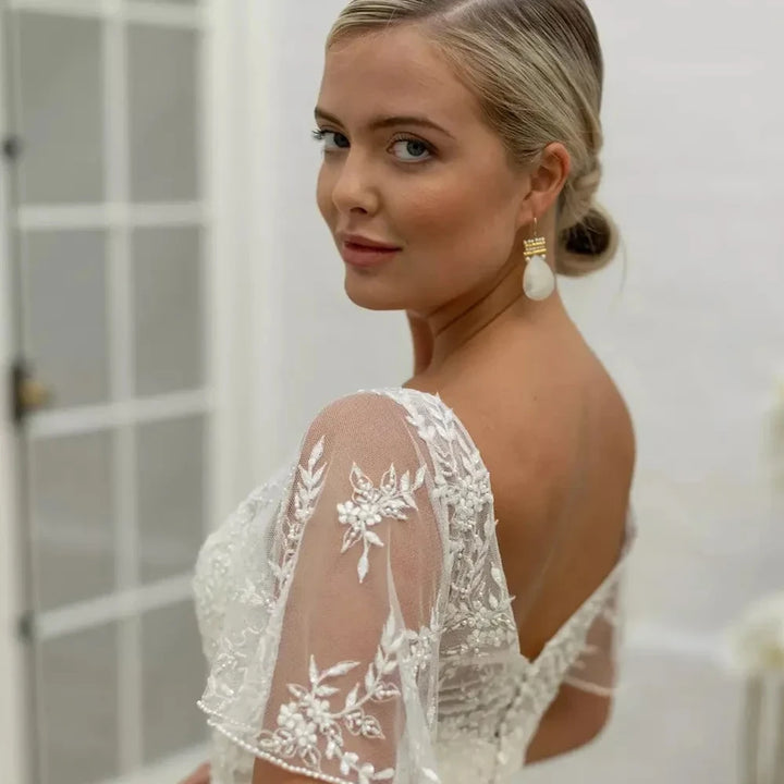 Ivory bridal dress bodice close-up with floral lace appliques on sheer sleeves