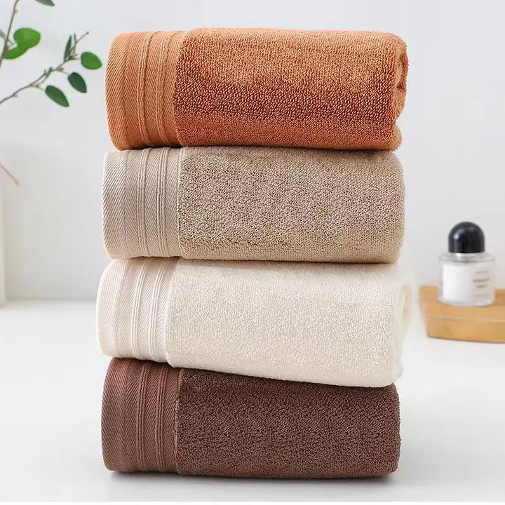 Folded cotton towels stacked in terracotta, light beige, and dark brown