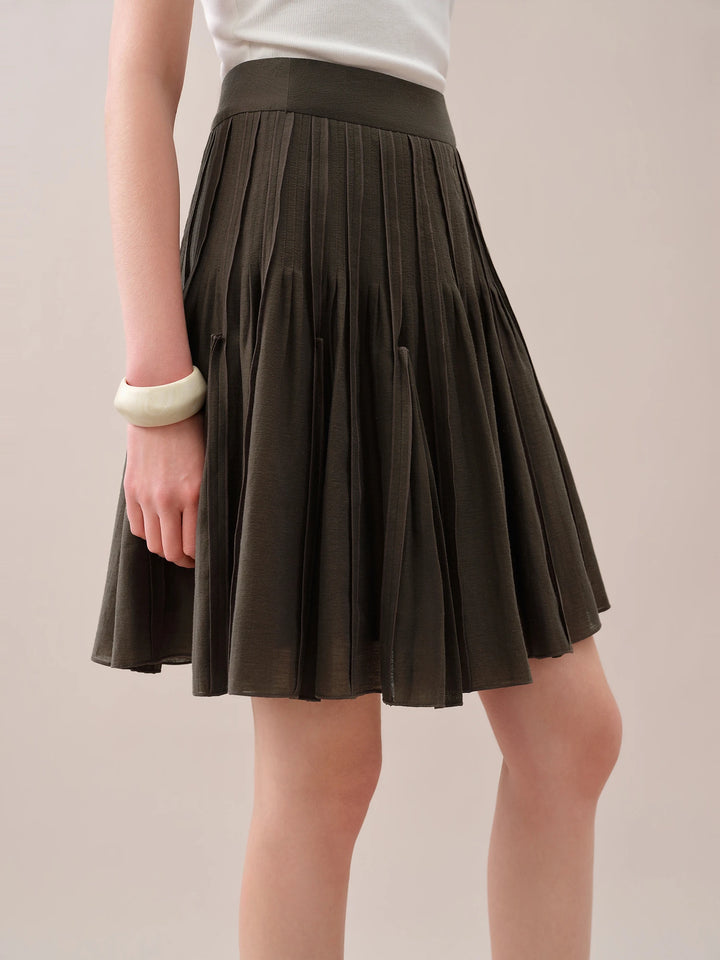Side view of dark brown pleated mini skirt with flared hem and elastic waistband