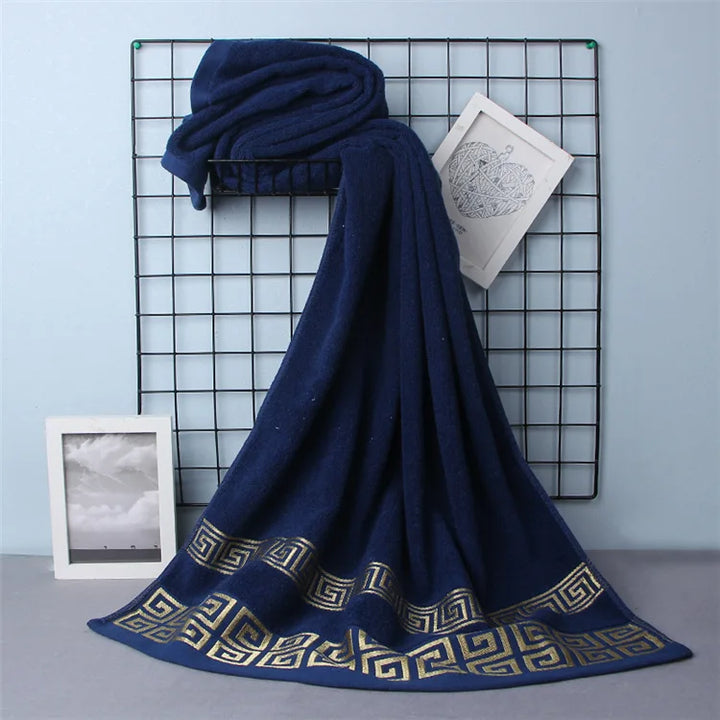 Cotton bathroom towel set in navy blue with gold Greek border, folded and draped.