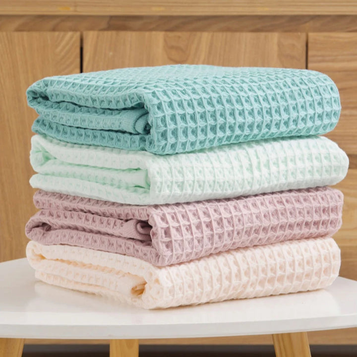Waffle knit cotton towel set, stacked rolled towels in teal, white, mauve, and light pink
