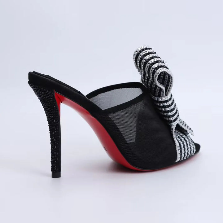Heel view black high-heel mule sandals with rhinestone-striped mesh bow strap and open toe