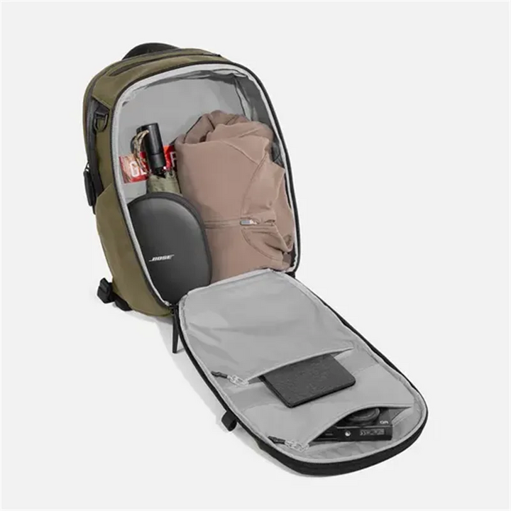 Olive green backpack open with gray-lined compartments and laptop sleeve for travel