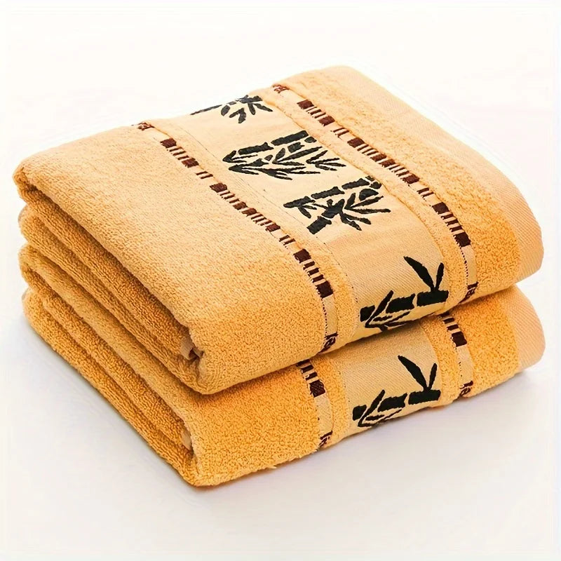 Stacked beige towels with black bamboo-pattern border and stitched trim