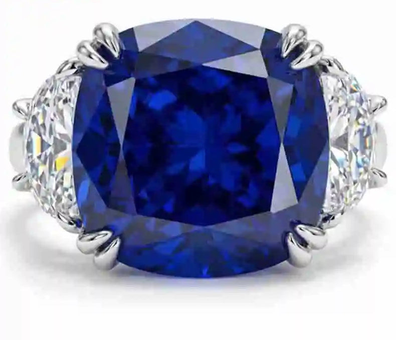 Ring with a large blue gemstone and smaller diamonds on a white background, featuring the brand 'Wong Rain'.