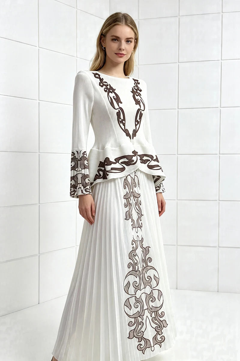 White two-piece pleated skirt set with long sleeves and dark ornate embroidered print