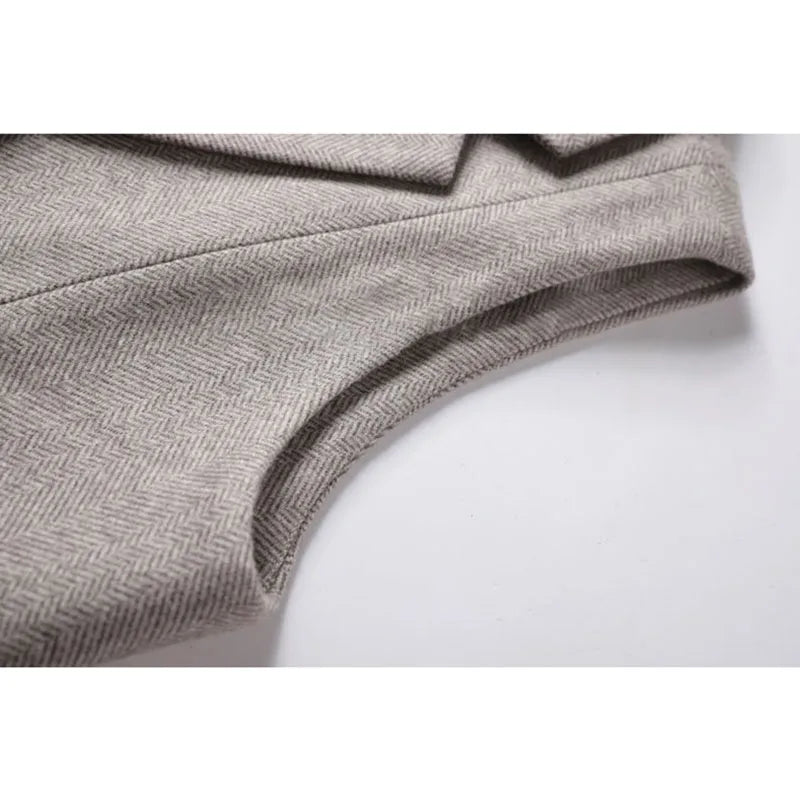 Gray herringbone waistcoat fabric close-up with curved stitched edge