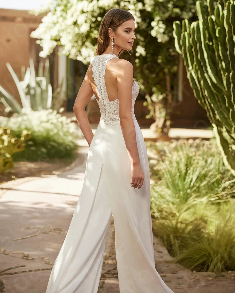 Woman in a white wedding dress standing in a desert garden with cacti.