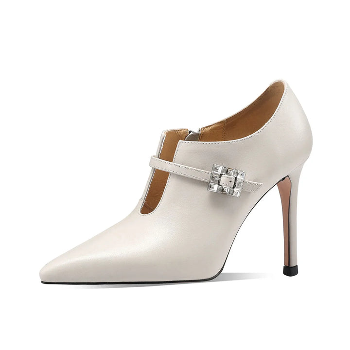 Beige pointed-toe pumps with stiletto heel and silver buckle strap detail