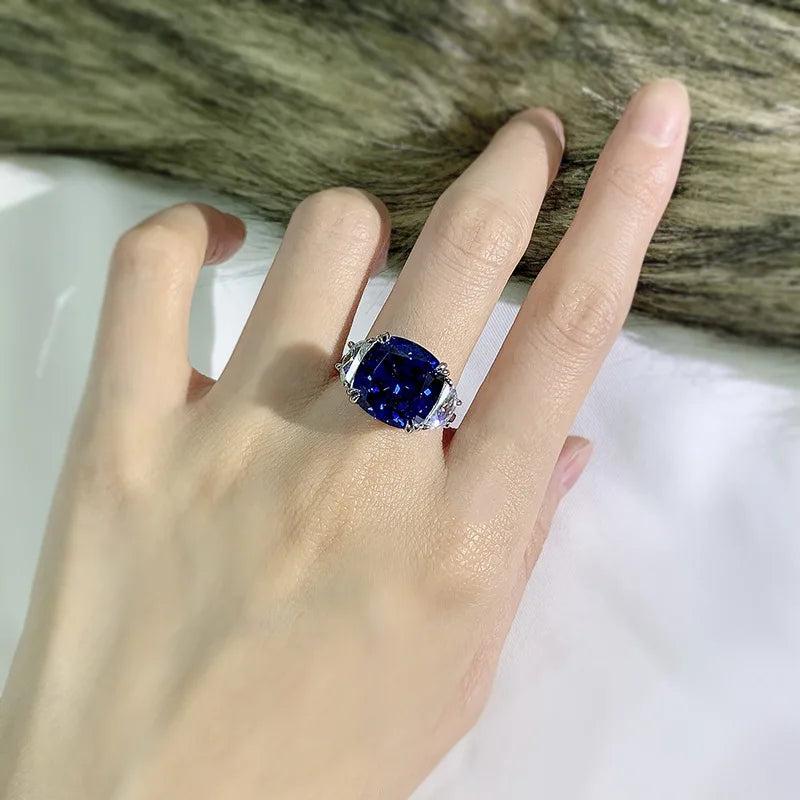 Sterling silver ring on hand with blue oval center stone and clear side accents