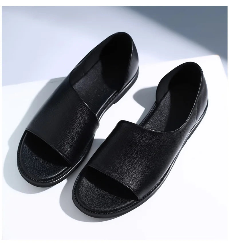 Black leather slip-on sandals with open toe, rounded strap, and rubber outsole