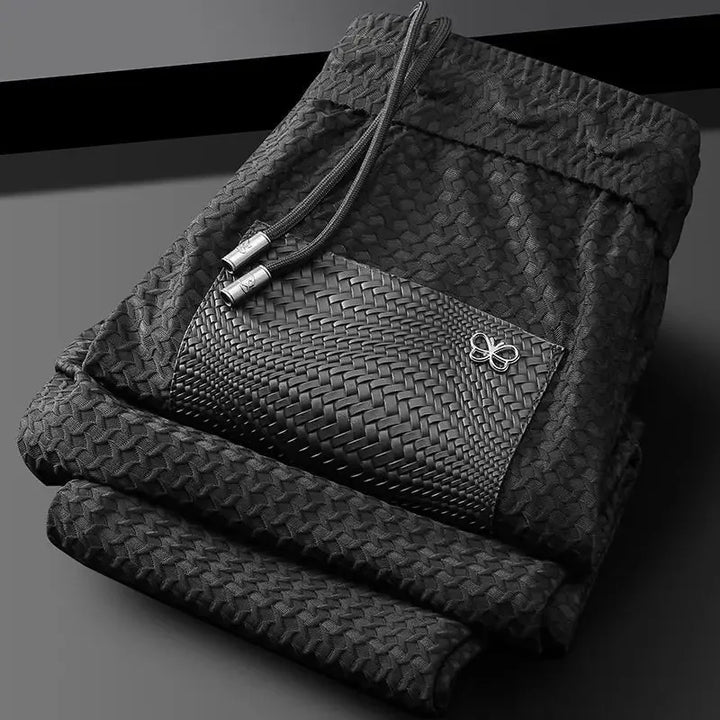 Black woven slim-fit trousers with textured pattern and bow emblem on pocket