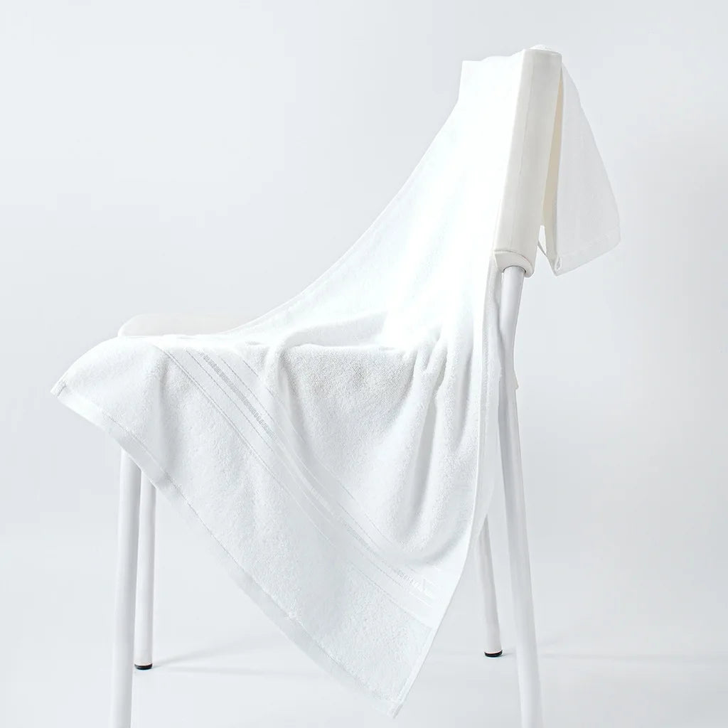 White cotton face towel draped over a stand, plush terry weave