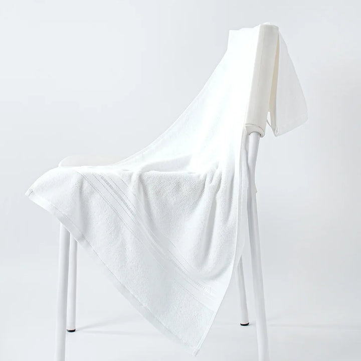 White cotton face towel draped over a stand, plush terry weave